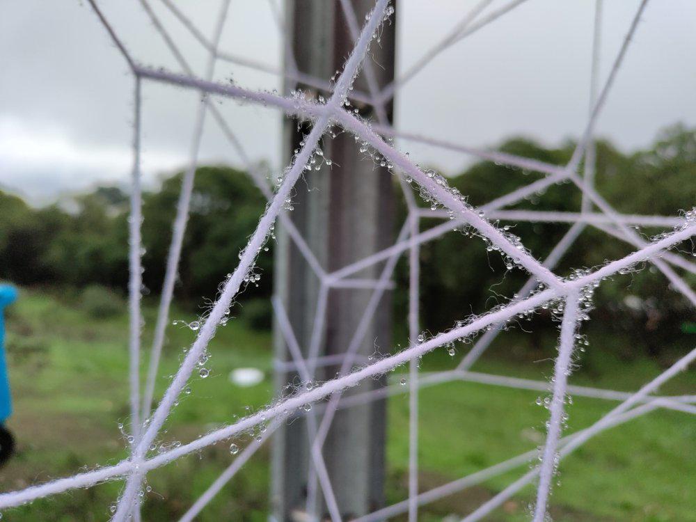 Crystaline looking web of heavy string in a bus stop, even closer showing dew